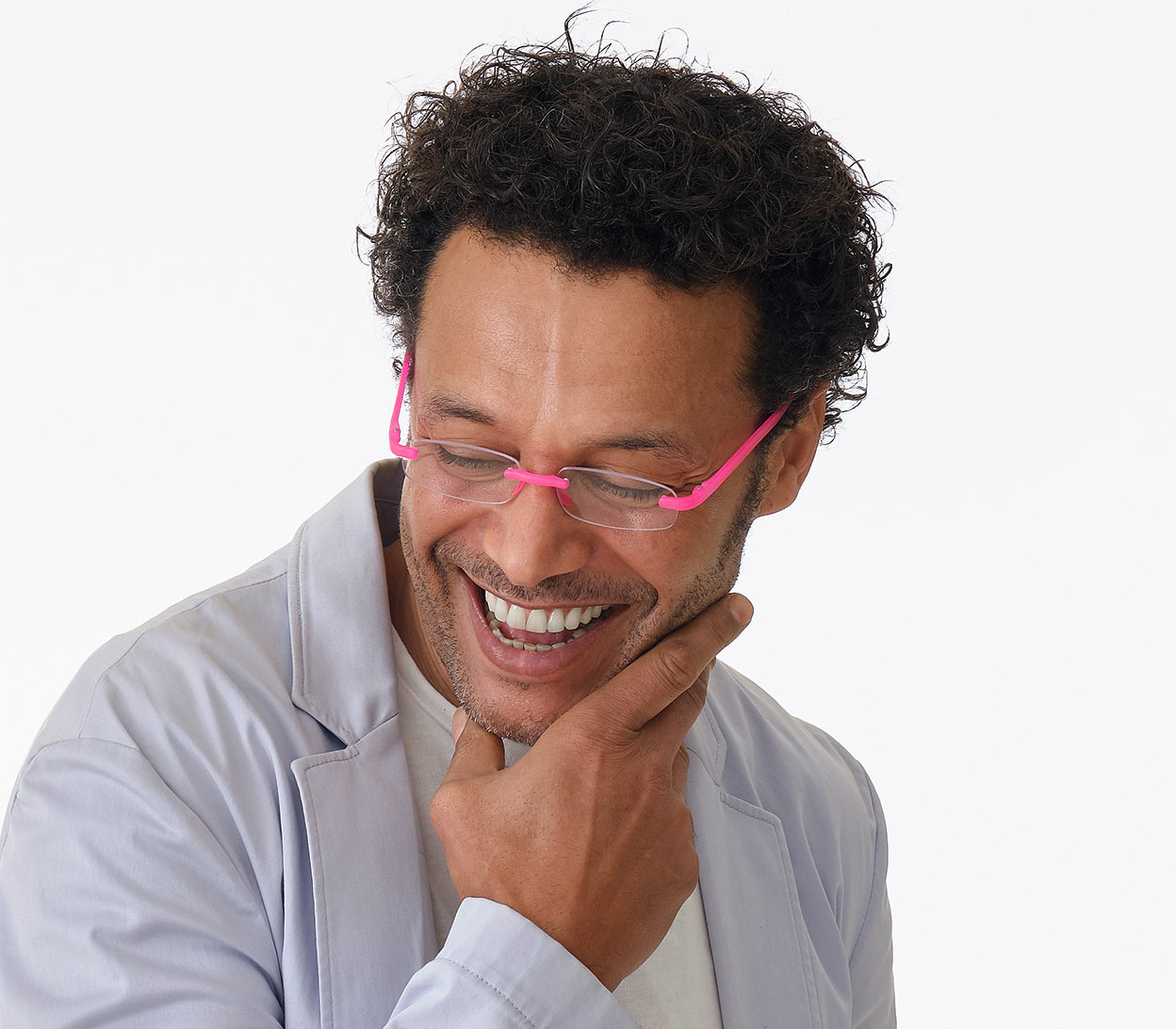 Male model wearing Jelli Neon (Pink) rimless, slim reading glasses with semi-translucent bright pink arms and bridge.