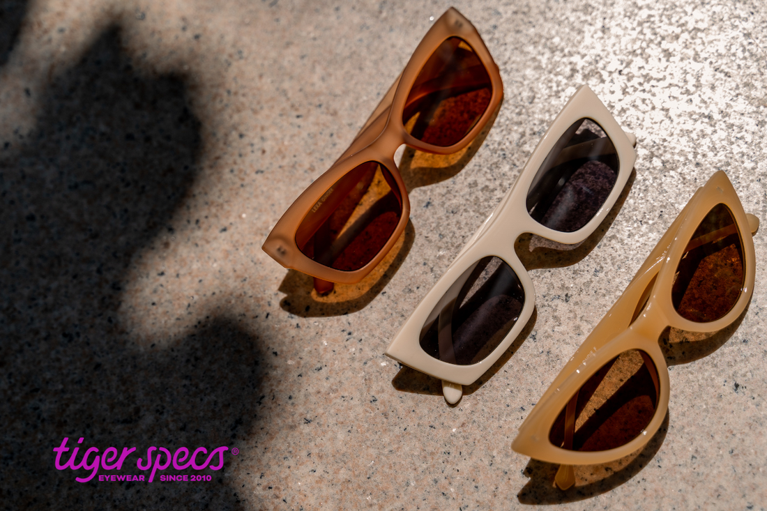 3 pairs of sunglasses on the sand.