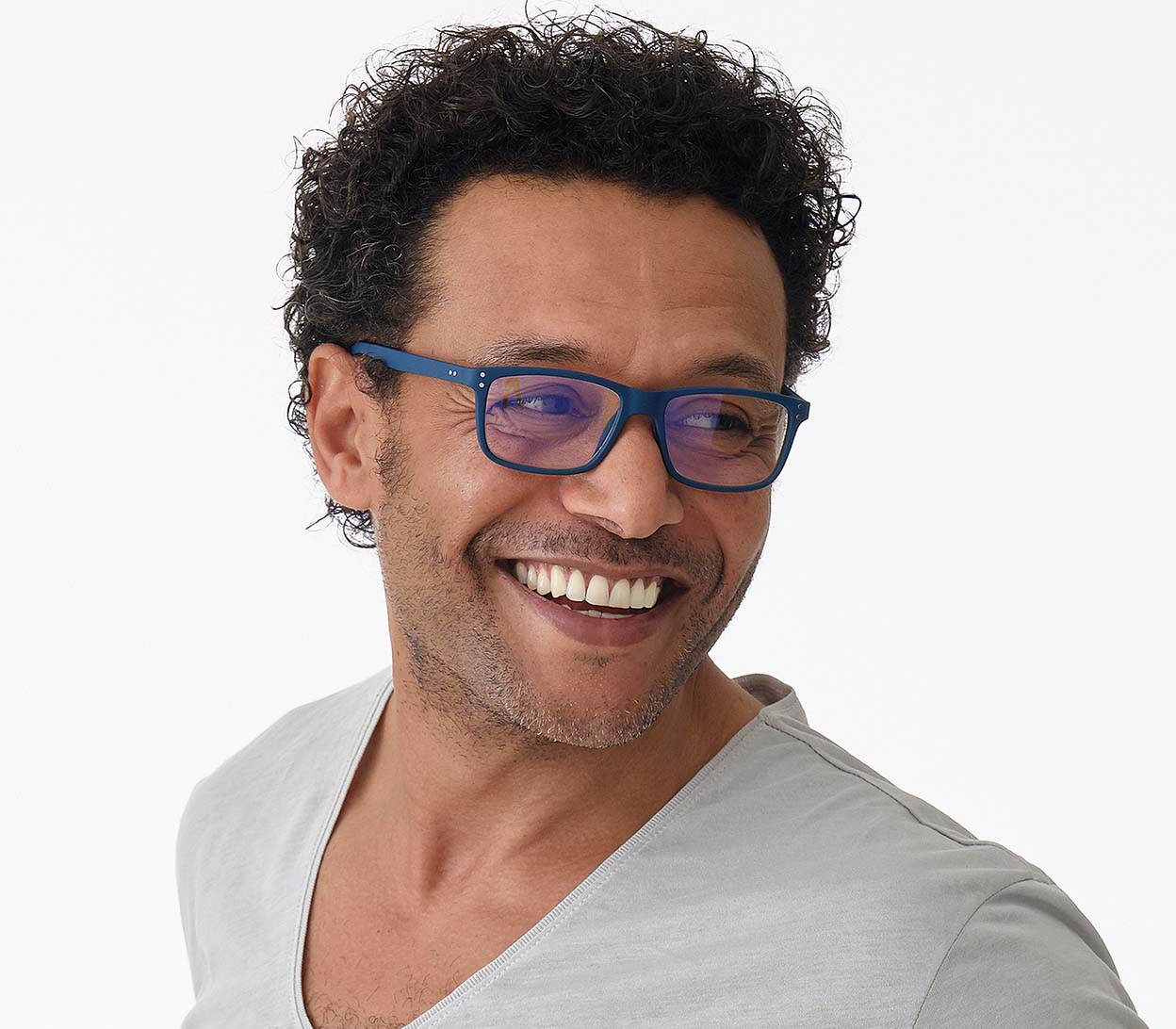 Male model wearing Austin (Blue) classic shaped, unisex blue light glasses. Deep blue frames with soft touch finish and rivet details.