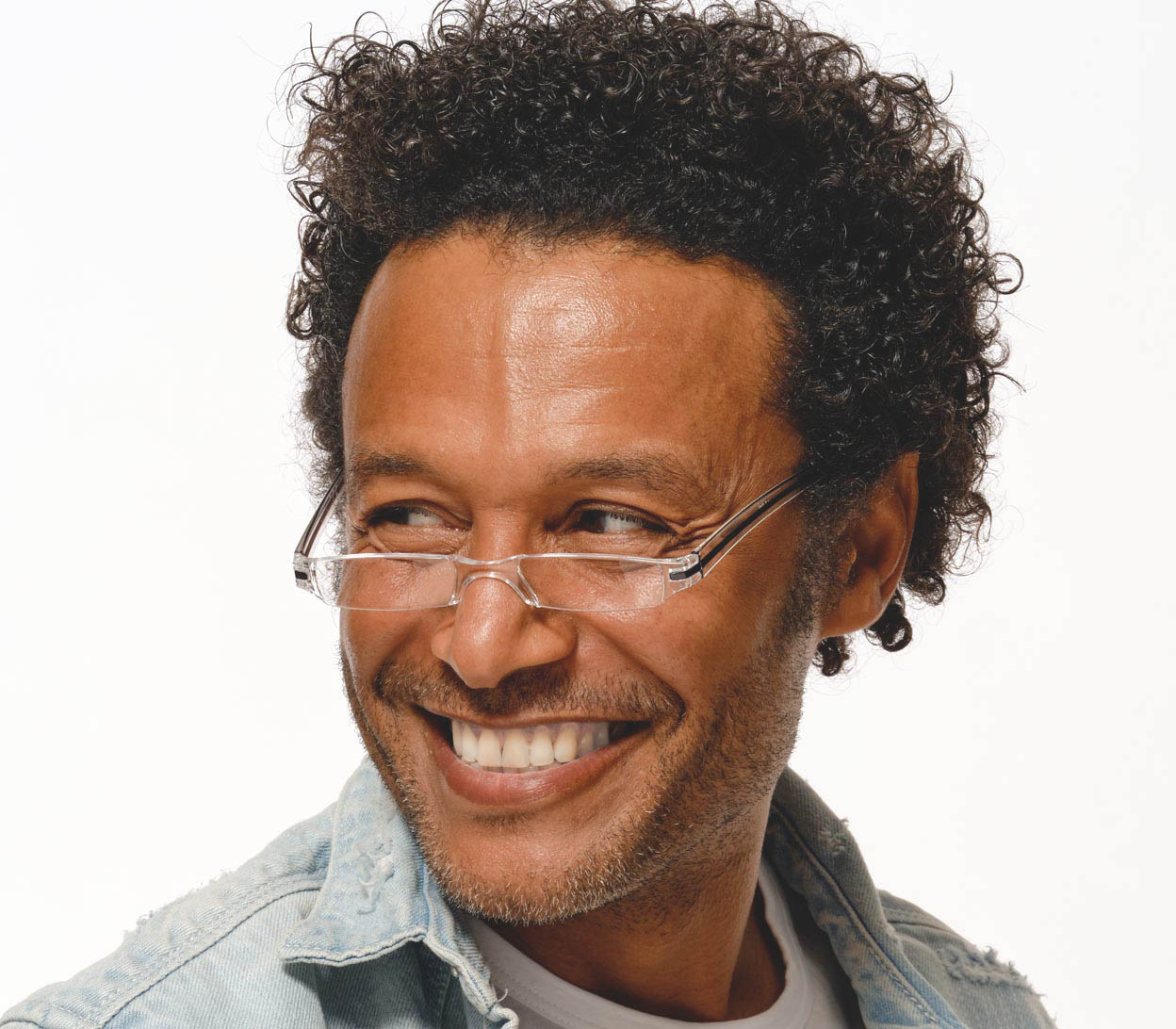 Male model wearing Soda (Black) seek, compact and ultra lightweight reading glasses with clear frames and black detailed temples.