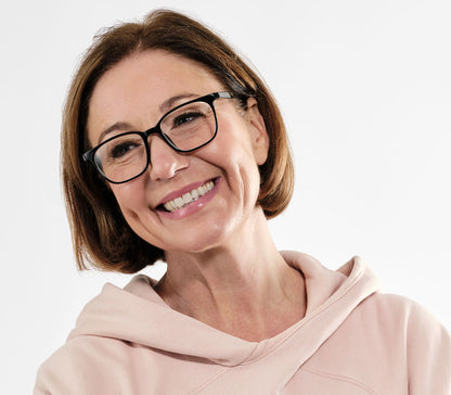 Female model wearing Artist Bifocal (Black) unisex reading glasses with glossy frame. Oval, bifocal lenses.