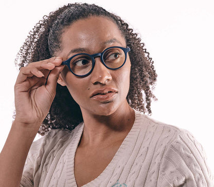 Female model wearing Oskar Digital (Blue) unisex reading glasses with large round blue light filtering lenses and soft touch deep blue frame.