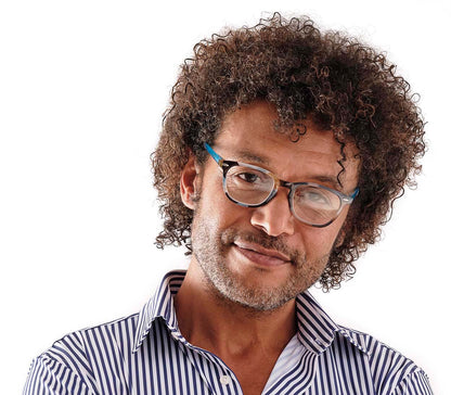 Male model wearing unisex reading glasses, retro shape with large oval lenses and blue, multicoloured pattern.