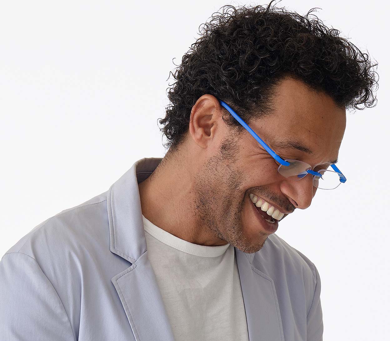 Male model wearing Jelli Neon (Blue) rimless, slim reading glasses with semi-translucent bright blue arms and bridge.