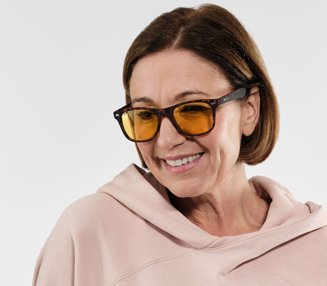 Female model wearing Grid (Tortoiseshell) classic wayfarer shaped night driving glasses. Wide arms and tortoiseshell pattern.