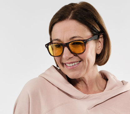 Female model wearing Grid (Tortoiseshell) classic wayfarer shaped night driving glasses. Wide arms and tortoiseshell pattern.