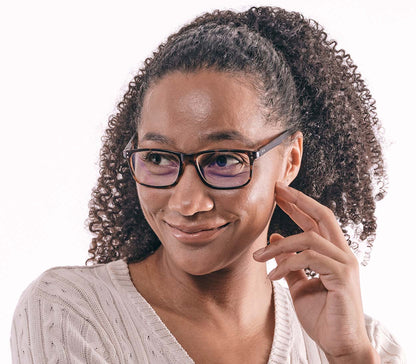 Female model wearing Austin (Tortoiseshell) classic shaped, unisex blue light glasses. Deep tortoiseshell frames with matt finish and rivet details.